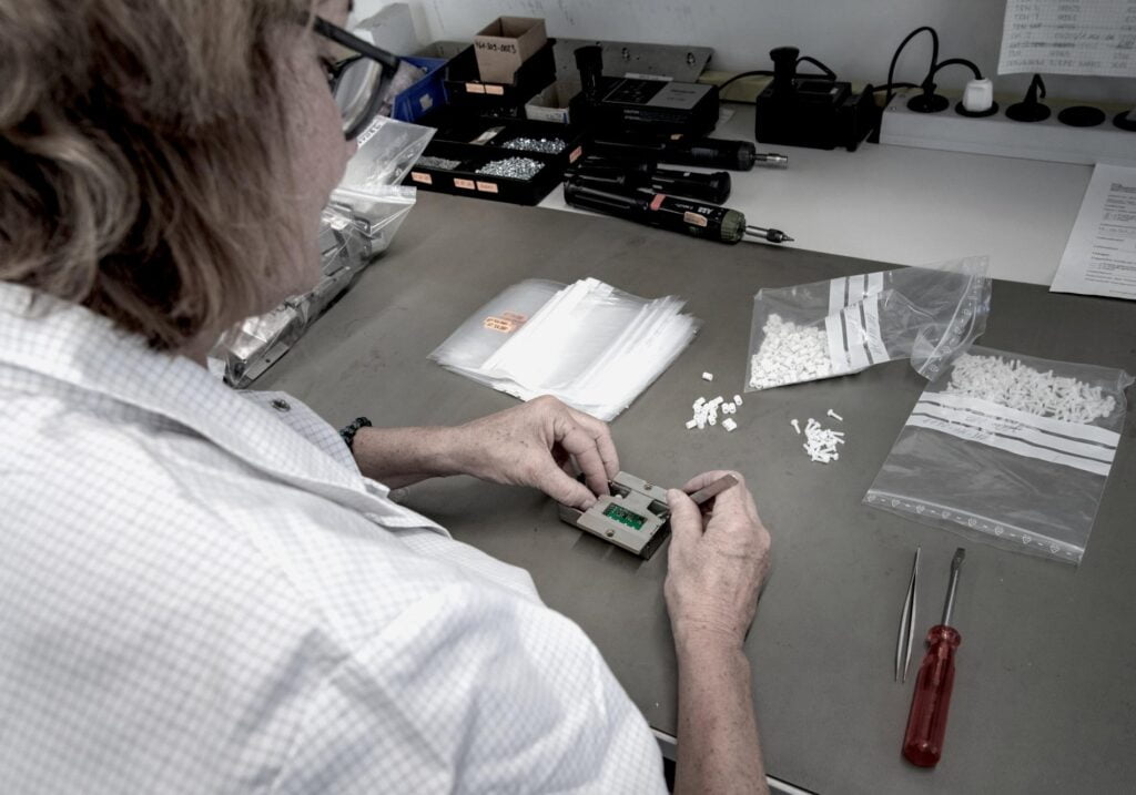 Mitarbeiterin bei der Montage eines elektronischen Bauteil in der Synetronics AG in der Schweiz.